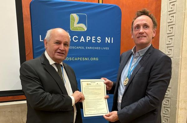 Two men hold up agreement document