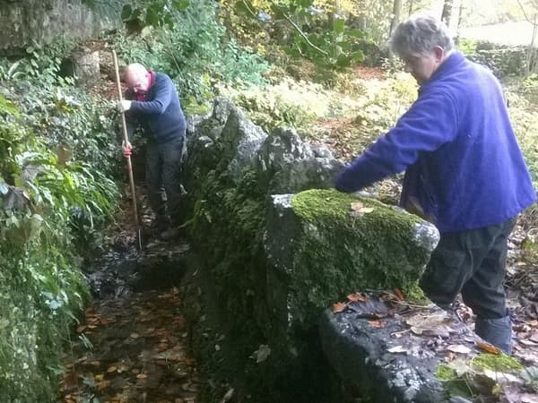 Two volunteers working on a stone wall